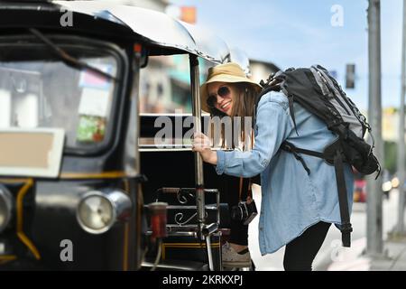 Image of caucasian woman tourist getting in local Tuk Tuk taxi for exploring the city in Thailand Stock Photo