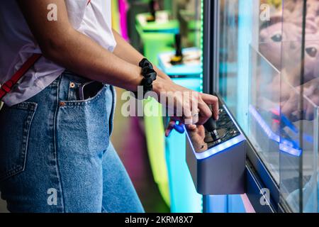 Side view anonymous young girl with long black hair playing in an arcade Stock Photo