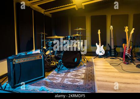 Contemporary music studio with electric and acoustic guitars placed on floor near amplifier and drums Stock Photo