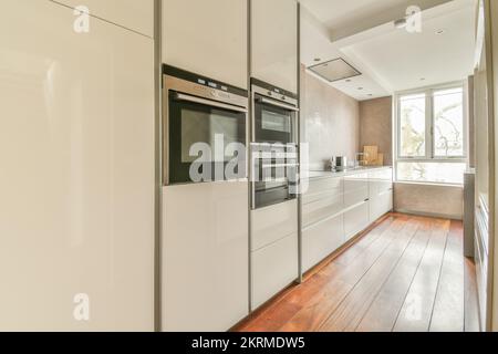 White counter with stove placed in stylish light kitchen with white cabinets near white fridge at home Stock Photo