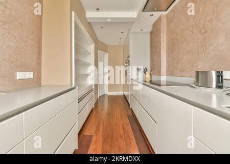 White counter with stove placed in stylish light kitchen with white cabinets near white fridge at home Stock Photo