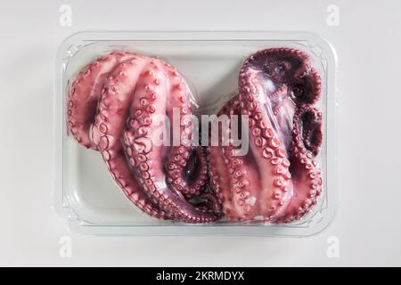 Top view of raw pink octopus placed in plastic box on white background Stock Photo