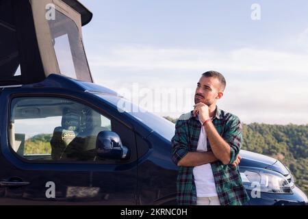 man leaning on his camper van observing nature Stock Photo