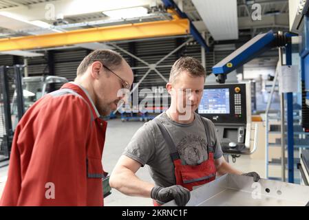 teamwork in the metal industry - two workers and engineer talking about work in a metal construction company Stock Photo
