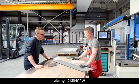 teamwork in the metal industry - two workers and engineer talking about work in a metal construction company Stock Photo