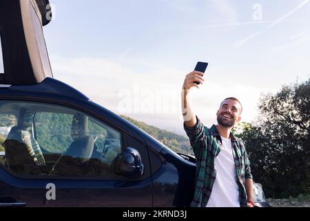 man taking a selfie leaning on his camper van Stock Photo