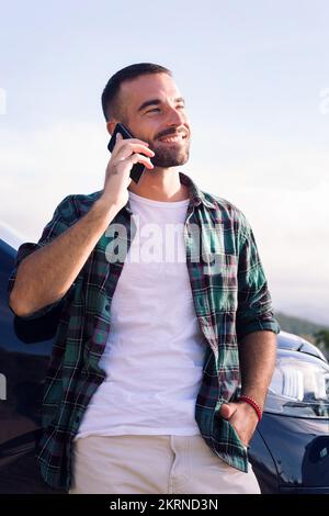 man talking on mobile phone leaning on his camper Stock Photo