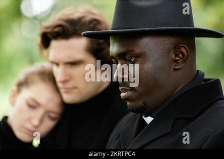 Side view portrait of African American priest holding ceremony at outdoor funeral Stock Photo