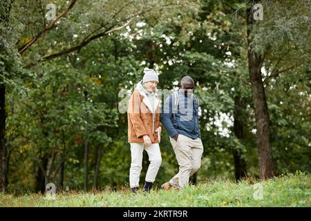 Full length portrait of smiling adult couple enjoying walk in autumn forest, copy space Stock Photo