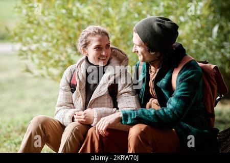 Portrait of loving couple sitting by tree while enjoying hike in forest Stock Photo