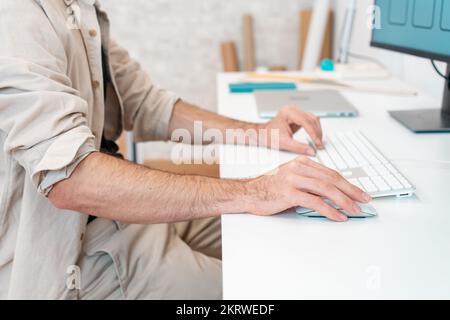 Unrecognizable man employee working on computer at desk in office. Stock Photo