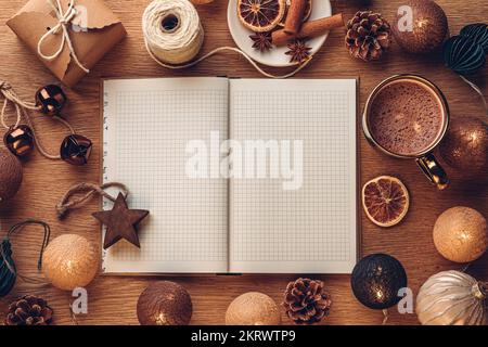 Open notebook on oak wood background with Christmas decoration and hot chocolate in a cup Stock Photo