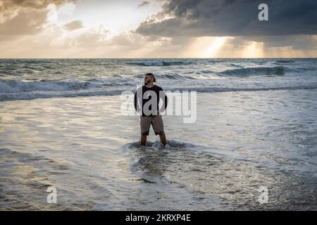 Hipster man with hands on waist at the beach. laid back attitude Stock Photo