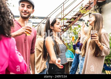 rooftop dancing party of young people, young generation females and males students having fun, drinking and chatting Stock Photo