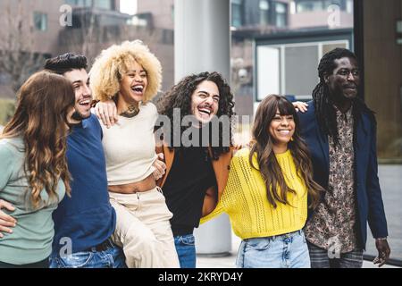 multiracial group of friends walking and having fun together, millennials people smiling and laughing in city context, social diversity people from th Stock Photo