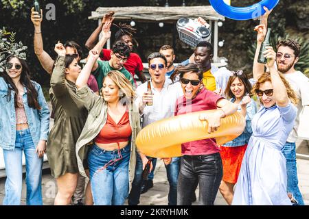 Big group of happy friends dancing and having fun at outside party, large mixed age range people celebrating holiday in a mansion, dancing and smiling Stock Photo