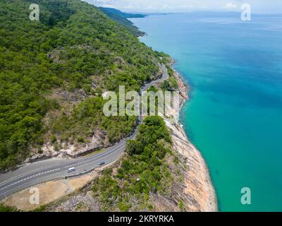 Aerial view of a winding road following the edge of a lush green lake ...