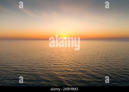 The sun casts golden light out over a body of water at dawn Stock Photo
