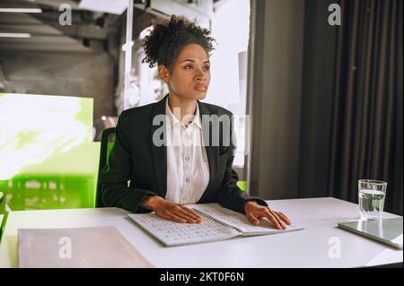 Woman sitting at table touching notebook Stock Photo