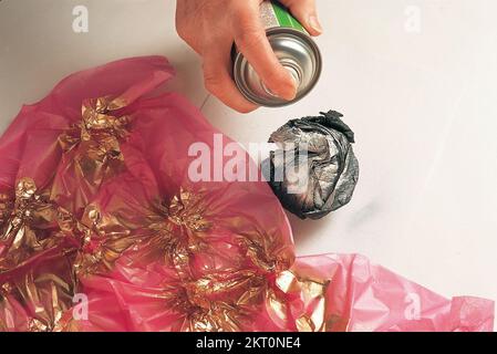 Spraying ball of black crepe paper with silver spray Stock Photo