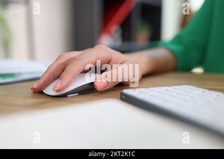 Close-up of woman's hand resting on modern wireless computer mouse. Stock Photo