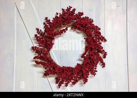 Red berry grapevine holiday wreath on a white barn door Stock Photo