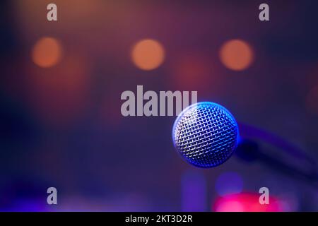 Close-up of lluminated microphone on stage against spotlights. Stock Photo