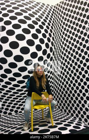 young protagonist posing on yellow chair and black and white psychedelic background in a modern room Stock Photo
