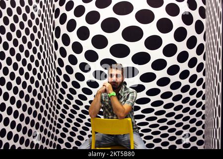 young protagonist posing on yellow chair and black and white psychedelic background in a modern room Stock Photo