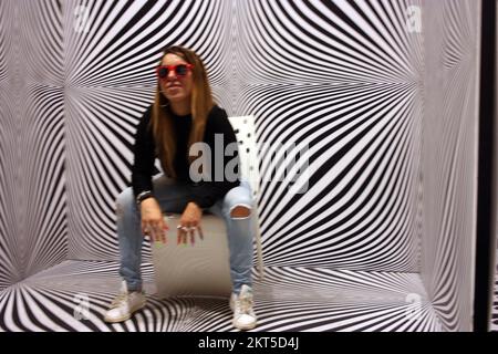 young protagonist posing on yellow chair and black and white psychedelic background in a modern room Stock Photo