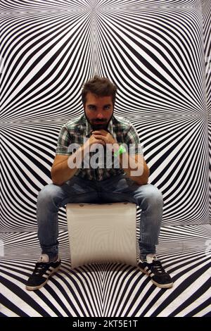 young protagonist posing on yellow chair and black and white psychedelic background in a modern room Stock Photo