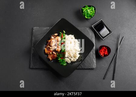 Kung Pao chicken or Gong Bao Ji Ding on a dark concrete background. Sichuan kung pao is a Chinese dish with chicken meat, chili peppers, peanuts Stock Photo