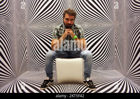 young protagonist posing on yellow chair and black and white psychedelic background in a modern room Stock Photo