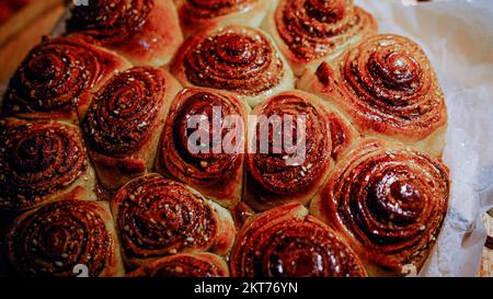 Freshly baked cinnamon buns with spices and cocoa filling on parchment paper. Top view. Sweet Homemade Pastry christmas baking. Close-up. Kanelbule - Stock Photo