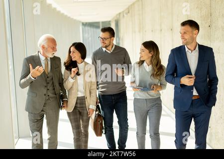 Group of corporate business professionals walking through office corridor on a sunny day Stock Photo