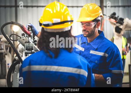 Two engineers mechanic using computer controller Robotic arm for welding steel in steel factory workshop. Industry robot programming software for auto Stock Photo