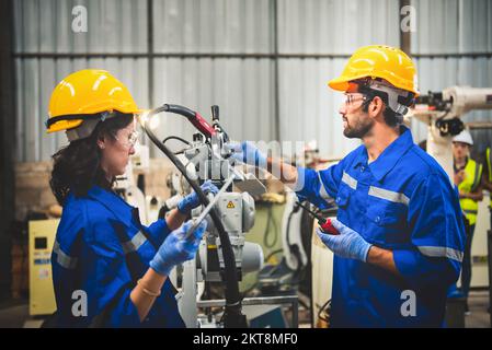 Two engineers mechanic using computer controller Robotic arm for welding steel in steel factory workshop. Industry robot programming software for auto Stock Photo