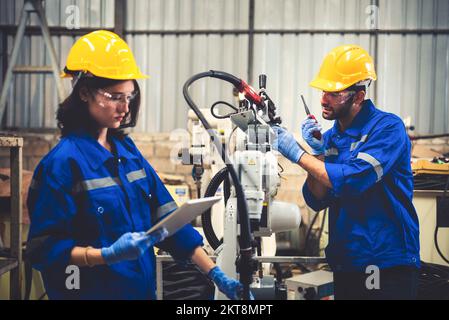 Two engineers mechanic using computer controller Robotic arm for welding steel in steel factory workshop. Industry robot programming software for auto Stock Photo
