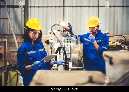 Two engineers mechanic using computer controller Robotic arm for welding steel in steel factory workshop. Industry robot programming software for auto Stock Photo