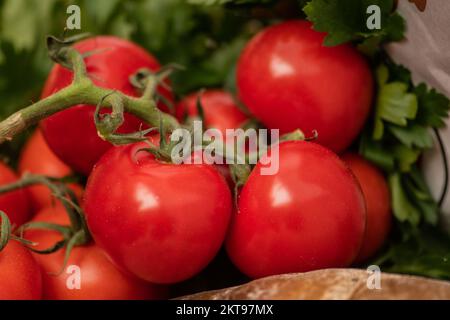 Fresh bio ripe red tomatoes with white bread, parsley and basil leaves in a wooden box in a street food market, close up Stock Photo