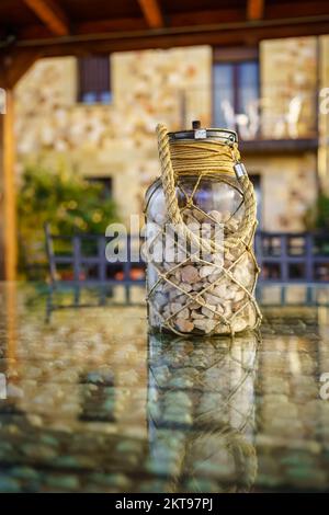 Glass jar with stones on top of a rustic country house table. Stock Photo