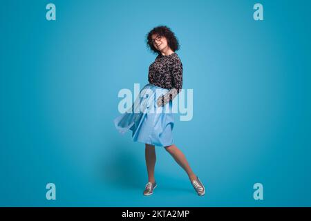 Photo of young beautiful happy smiling cheerful positive girl in skirt give interested flirty look isolated on blue color background. Positive emotion Stock Photo