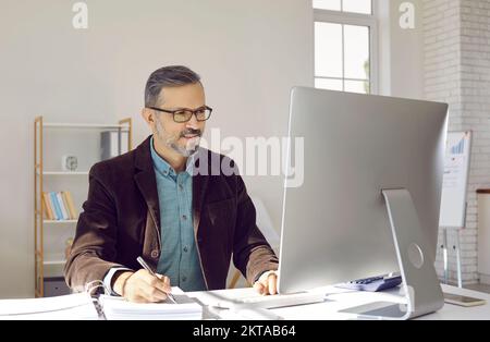 Mature businessman or financial accountant working on desktop computer in office Stock Photo