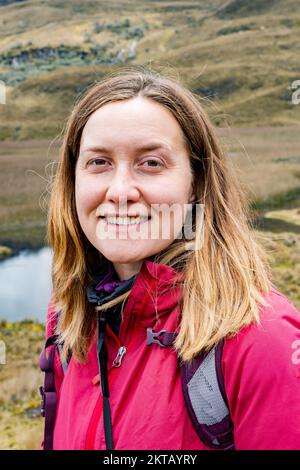 Close-up vertical photo of a happy female hiker in the Cajas National Park in the highlands of Ecuador, Cuenca, tropical Andes. Stock Photo