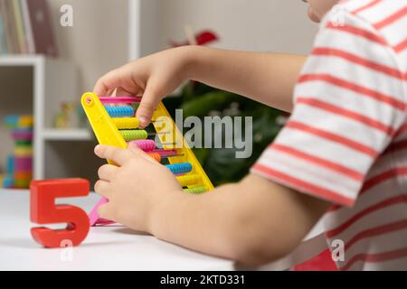 A small child learns to count on abacus, mathematics, arithmetic for children. Stock Photo