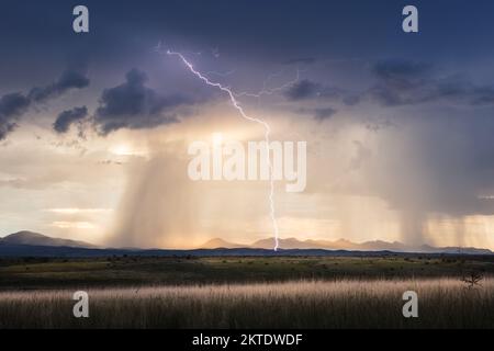 Stormy sky with lightning, dramatic clouds and golden sunlight over a field near Sonoita, Arizona Stock Photo