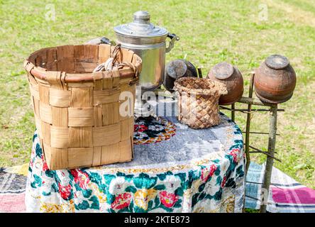 Vintage wicker handmade basket, samovar and utensils of pottery outdoors Stock Photo