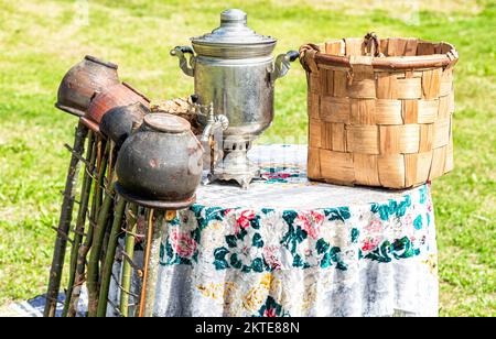 Vintage wicker handmade basket, samovar and utensils of pottery outdoors Stock Photo