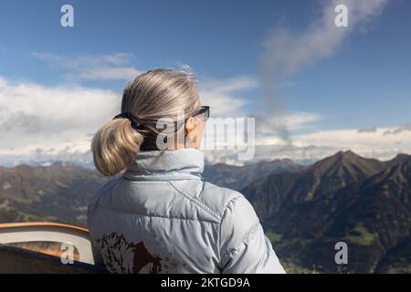 Gray-haired woman sits on a bench at cloud level, alps, austria. High quality photo Stock Photo