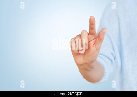 Female hand touching the virtual button with forefinger on blue background.  Stock Photo